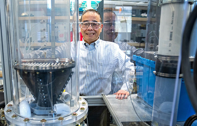 A man stands in a lab next to a solid-particle energy storage device