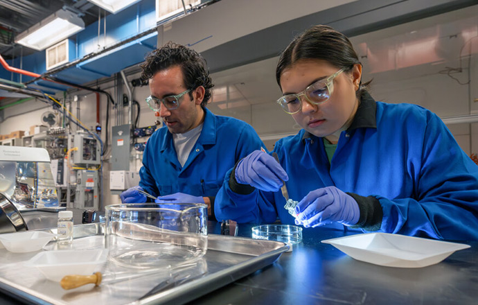 Two people at a lab bench examine plastic particles from river water samples
