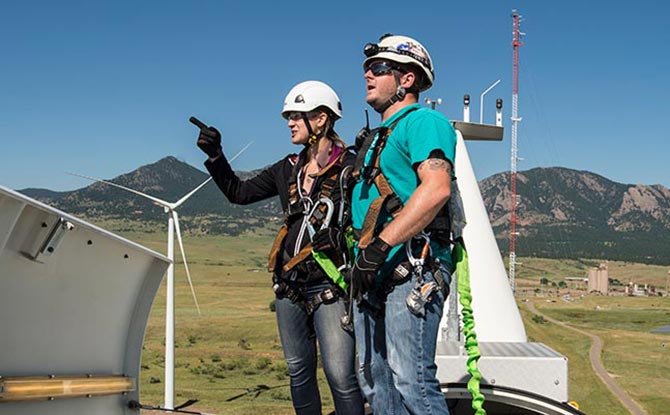 Two NREL scientists on top of a wind turbine.