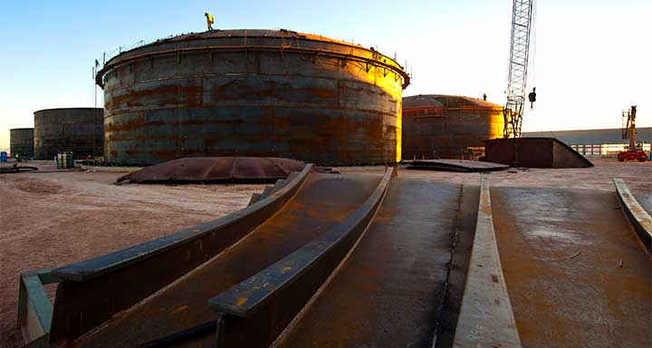 Sun sets on a group of large, circular tanks.