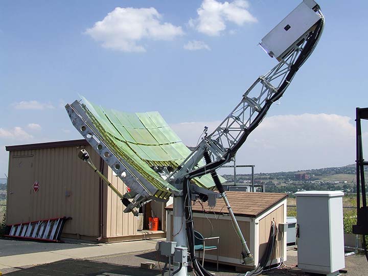 A piece of equipment features a parabolic dish and sits outdoors in the twilight.