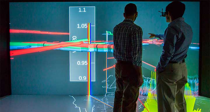 Two people looking at a data visualization projected on a screen.