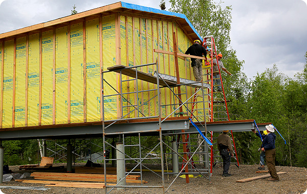 Photo of workers building a raised house.