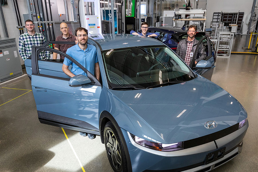 Group of people stand inside lab around the Hyundai Ioniq 5 electric vehicle.