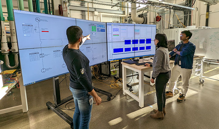 Three researchers look at data screens in a lab.