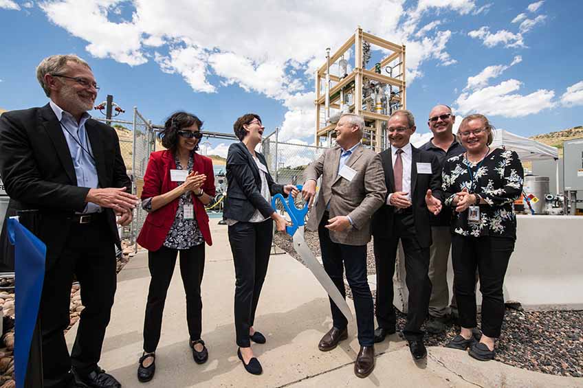 Group of people cut a ribbon to dedicate the bioreactor in the hydrogen facility at the Energy Systems Integration Facility.