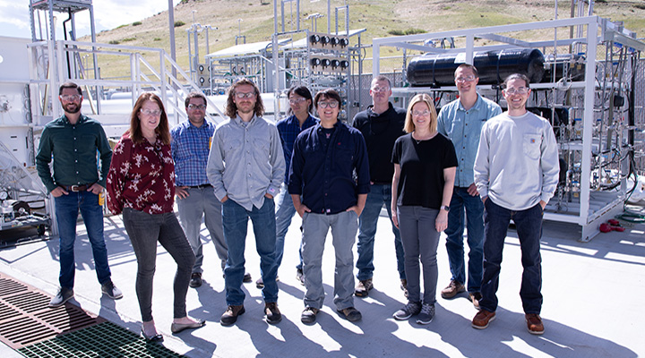 Group of researchers stand outside power grid system