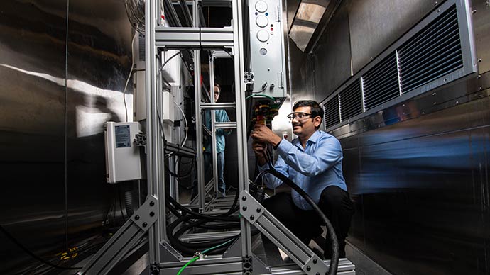 A researcher works with a residential battery test bed in an environmental chamber