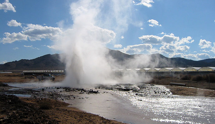 Steam erupting from natural geothermal hot spot in ground.
