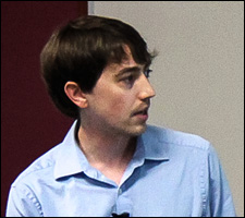 A photo of a young man in a blue shirt pointing to something on a presentation.