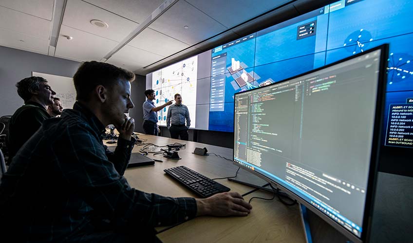 Researchers in cybersecurity visualization lab evaluating a virtual grid environment.
