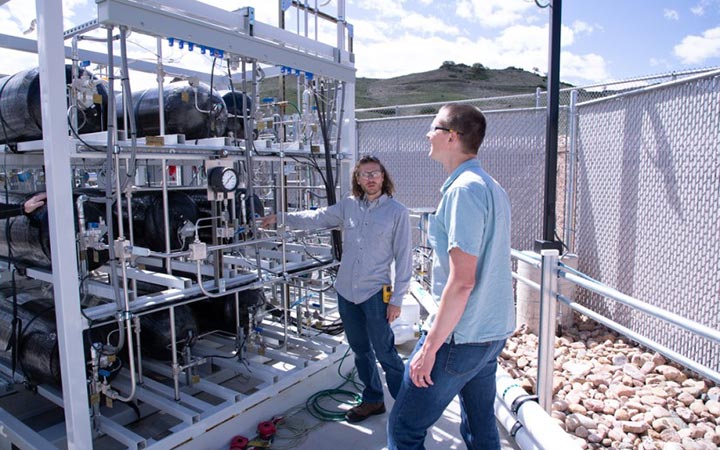 Two researchers stand in front of NREL's heavy-duty hydrogen fueling station. 