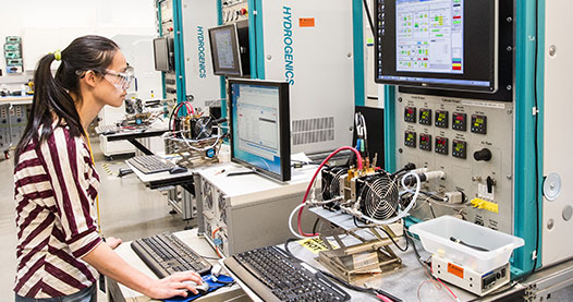 Photo of a researcher in a laboratory running a test on a fuel cell test stand.