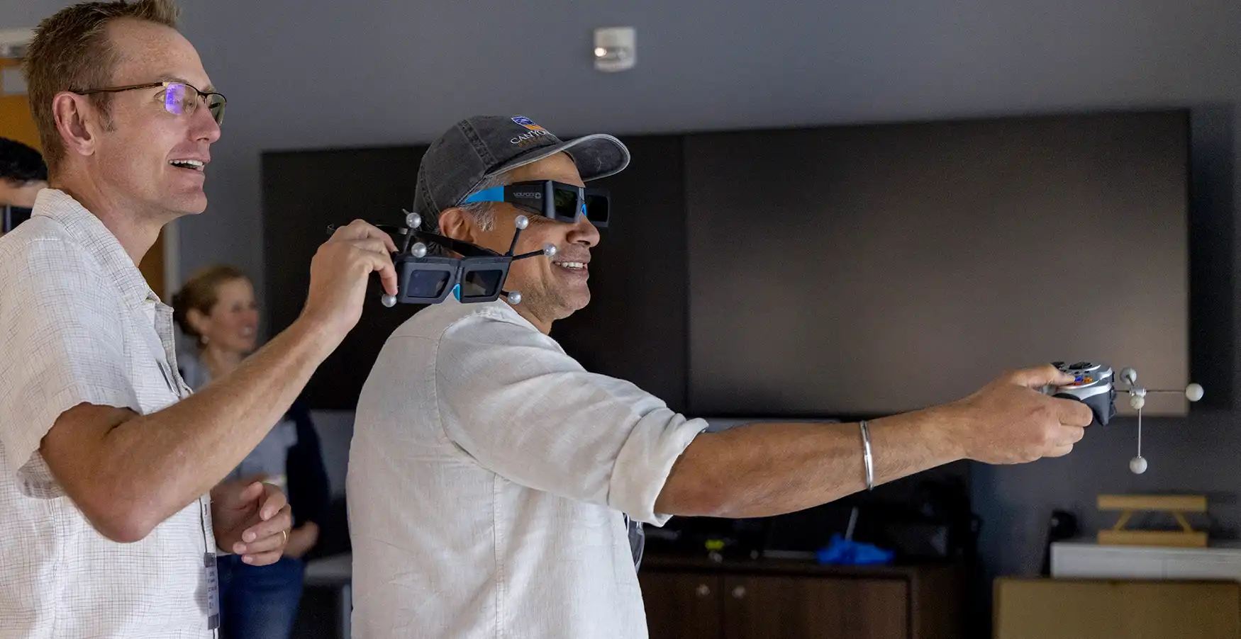 A person holds custom glasses as another person points a controller in front of them.