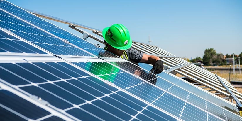 40820 A worker installs photovoltaic panels in a large outdoor solar array.