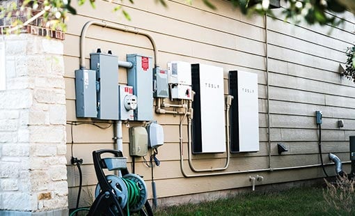 istock-1296608279-feature Photo of a Tesla power wall on the side of a house.