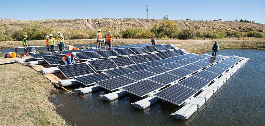 Workers install solar panels on water.