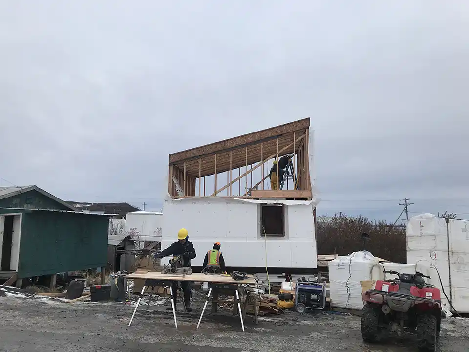 Construction workers work on a house.