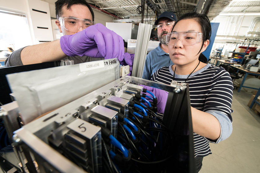 brand-photo-60783 Three people in a laboratory handle objects while wearing gloves and protective eyewear.