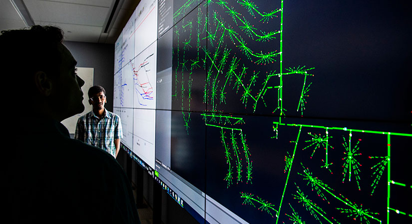 reinforcement-learning-52714 Two researchers view a data visualization display of a multi-timescale simulation for evaluating real-time grid control challenges.