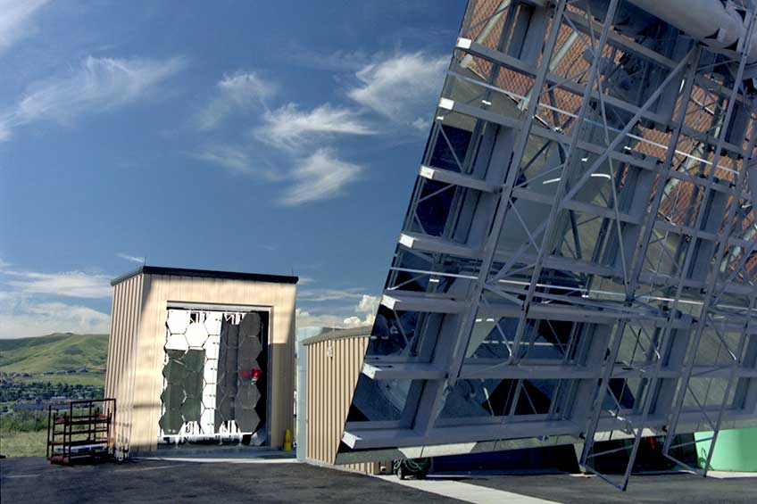201908-hfsf Photo of the high-flux solar furnace concave mirrors and heliostat in front of a blue sky.