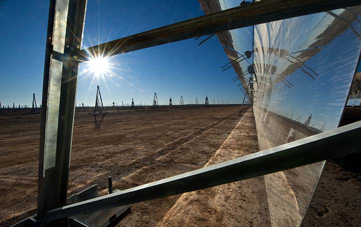 201909-20098-720 A reflective parabolic trough from the side as the sun gleams further downfield.