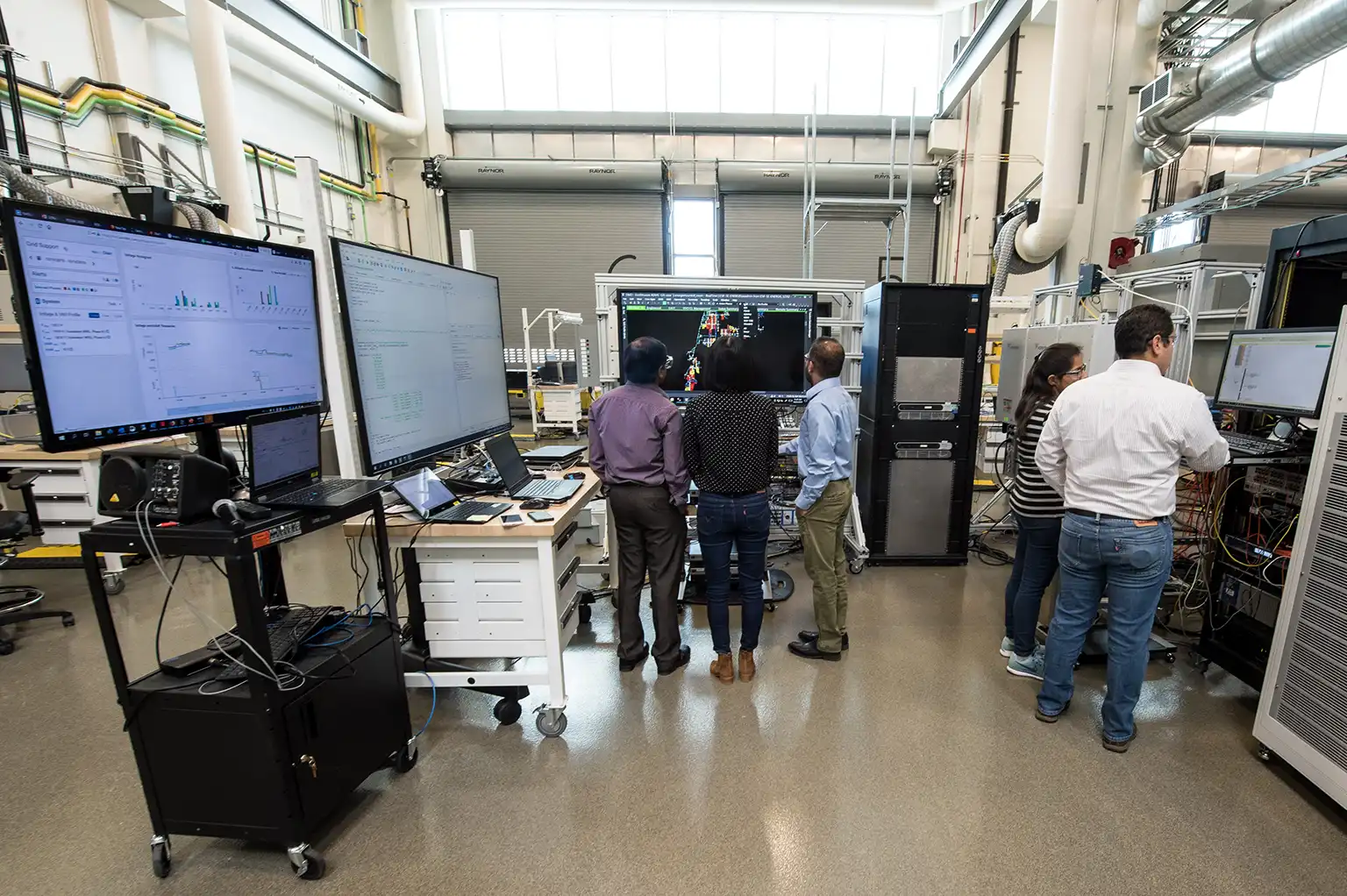 Researchers in a lab looking at data on a large monitor.