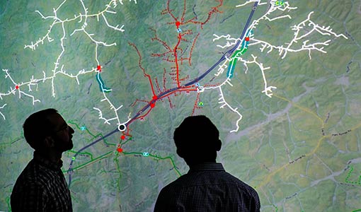 power-systems-design-studies-34479-thumbnail Photo of two researchers looking at a screen showing a distribution grid map