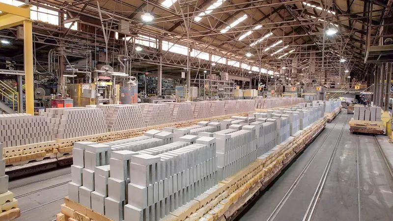 A large warehouse containing rows of cement blocks on pallets.