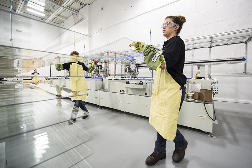 Two workers move large sheets of
