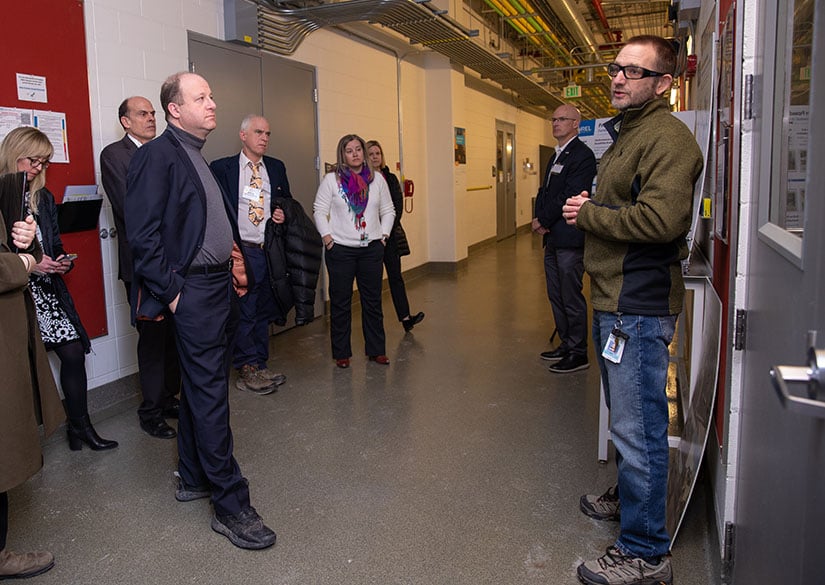 A group of people listen to a researcher although on a tour of NREL.