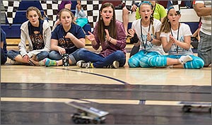 Photo of a group of students watching a race between solar-powered cars.