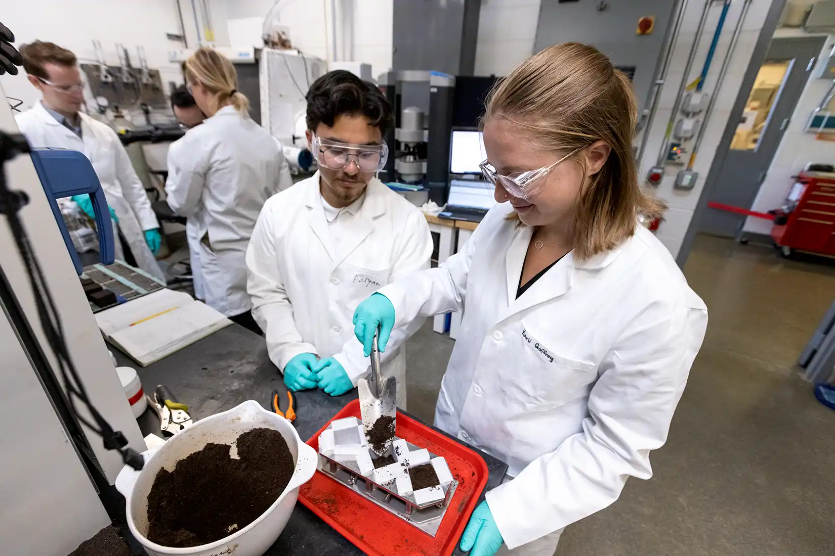 Two people in lab coats and safety glasses.