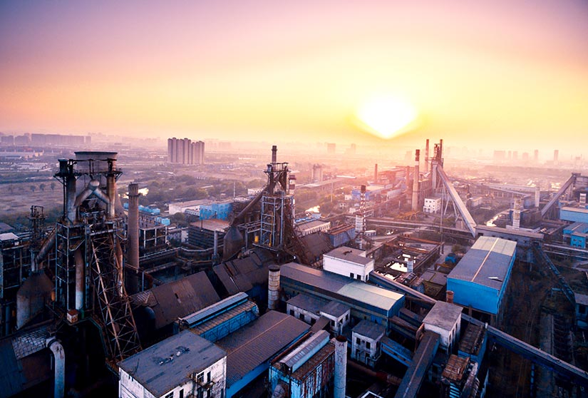 Photo of the sun setting over an industrial city.