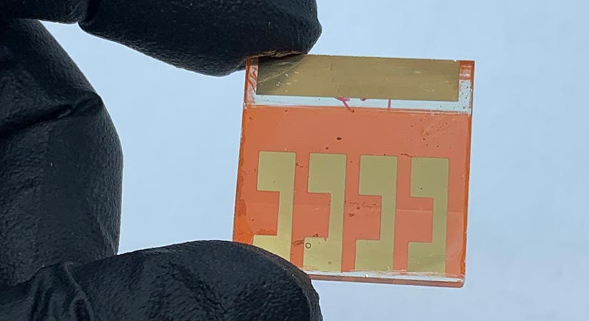 Fingers holding an orange perovskite.