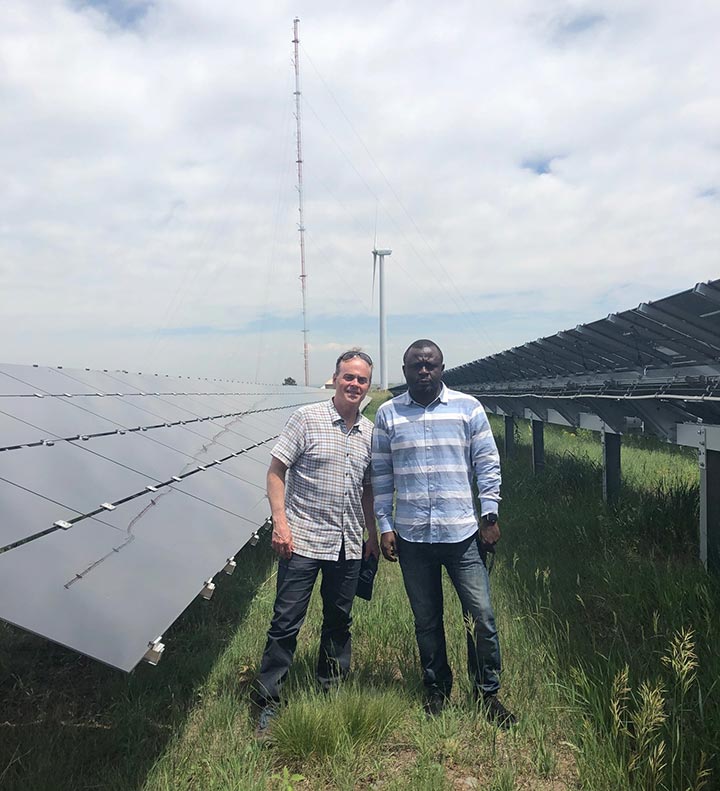 A picture of David Corbus, NREL, and Peter Acheampong, BPA, standing in grass next to solar panels at NREL's Flatirons Campus.