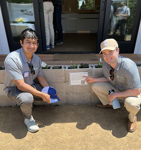 Two men crouch next to cinder blocks.