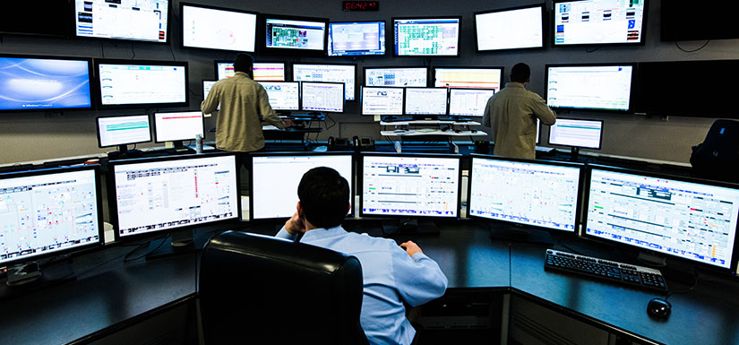 Workers reviewing security footage on multiple monitors.