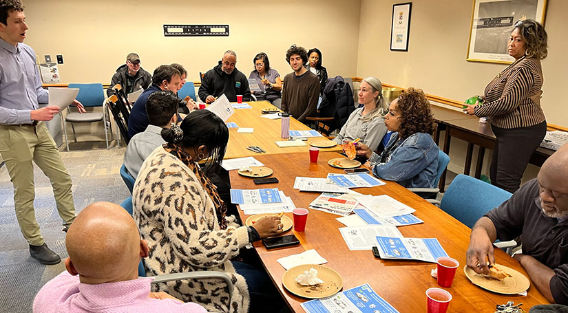 People sit around a conference table with food and flyers
