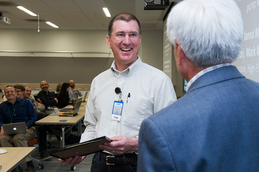 20250505-nrel-researcher-craig-turchi-brings-small-business-experience-to-big-concentrating-solar-projects-award-33074 A person smiles while receiving an award in front of a group of people.
