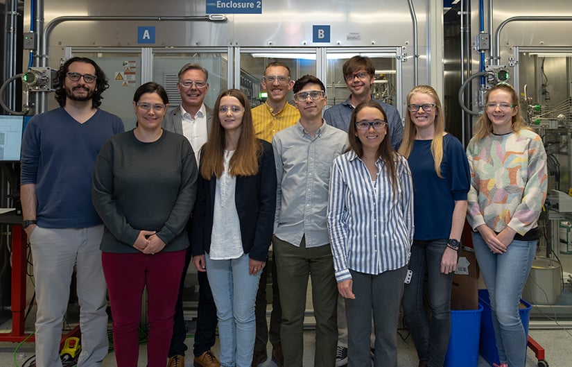 20250610-plastics-recycling-with-enzymes-takes-a-leap-forward-99618 Ten people stand in front of laboratory equipment.