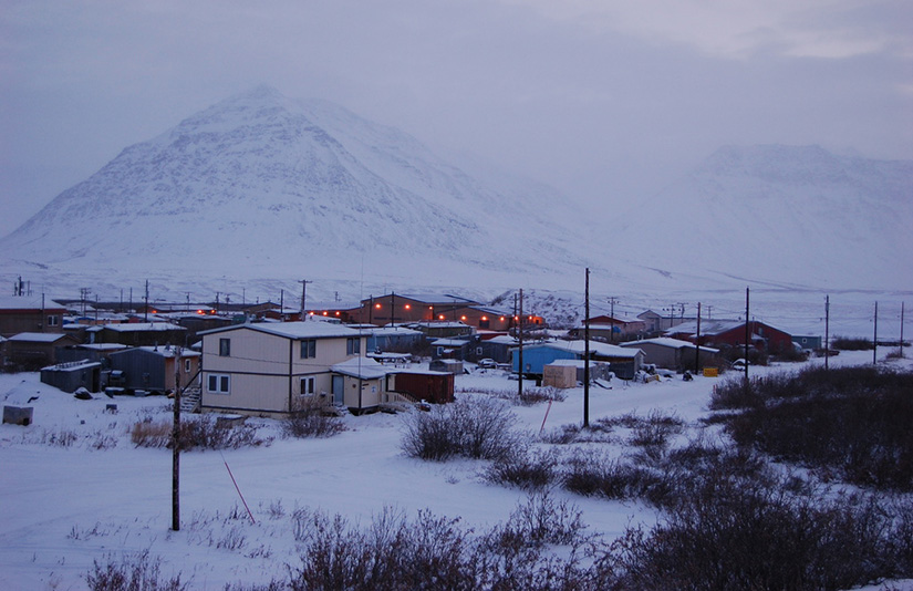 20250701-nrel-modeling-shows-geothermal-borehole-68659 Village of Anaktuvuk Pass, Alaska, in winter, with snow-covered ground, houses, and mountains in the background.