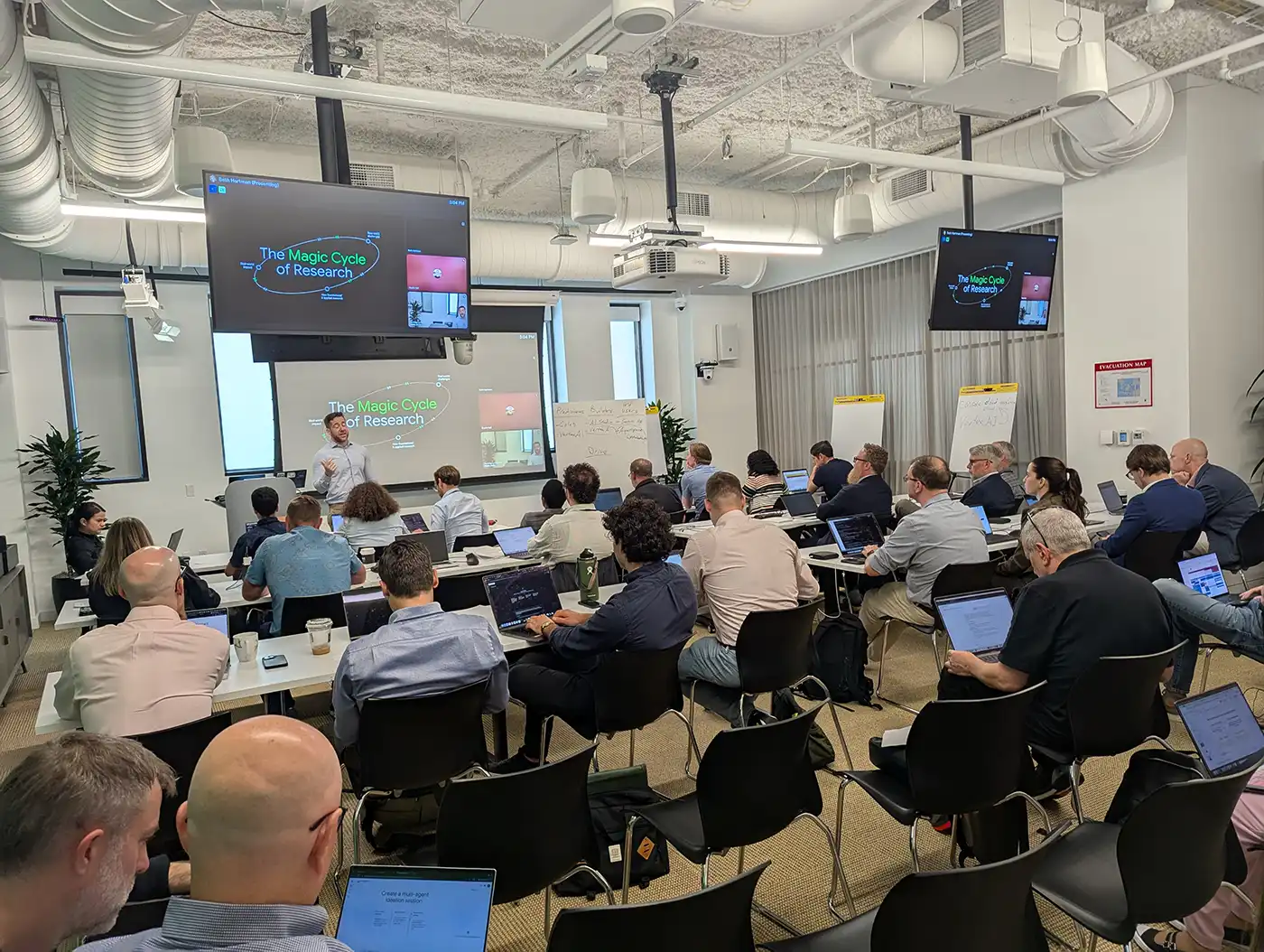20250722-nrel-google-host-artificial-intelligence-hackathon-tackle-data-center-energy-challenges-group A large room full of people seated while watching a speaker present information