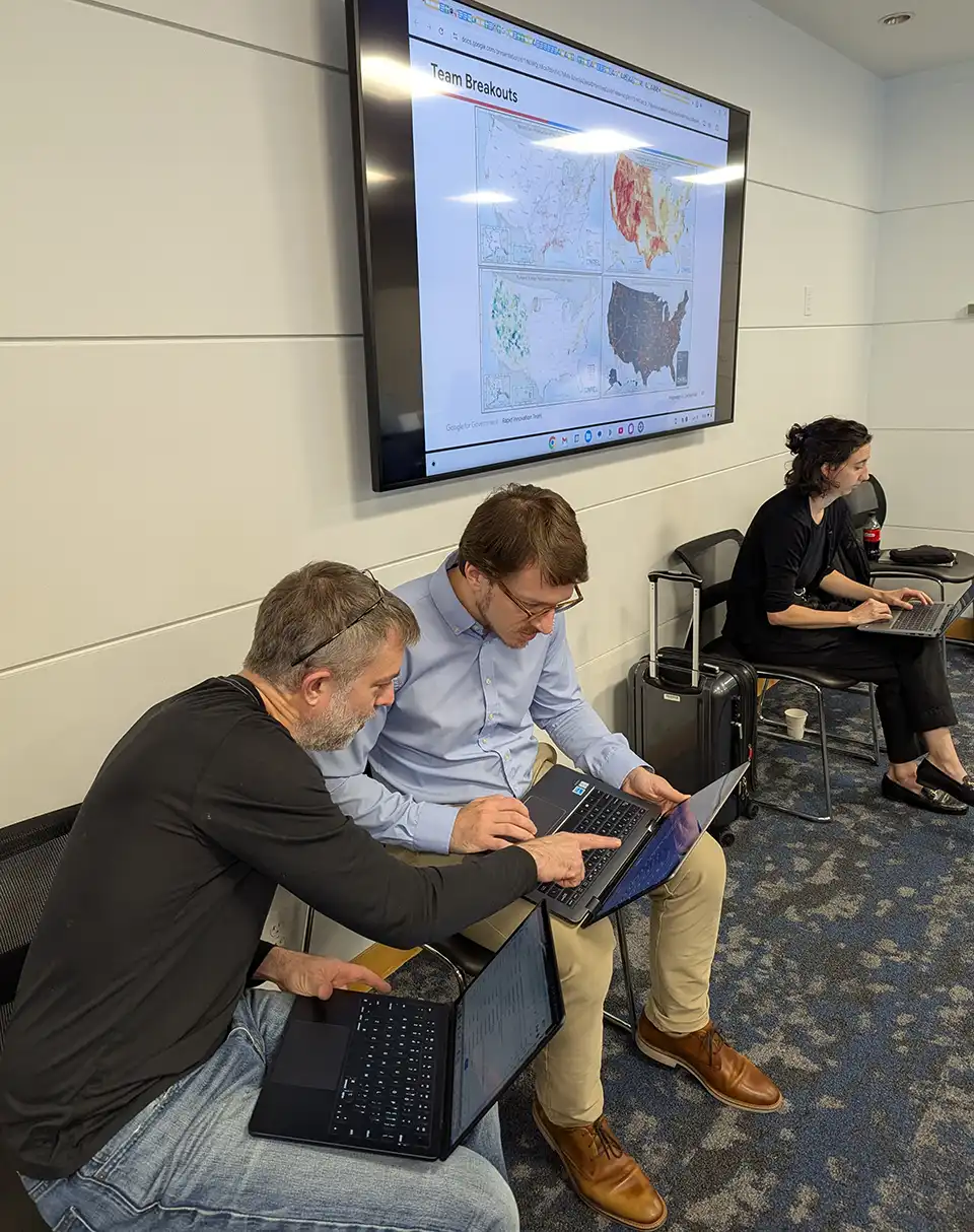 20250722-nrel-google-host-artificial-intelligence-hackathon-tackle-data-center-energy-challenges-laptops Three people are seated while working on laptops
