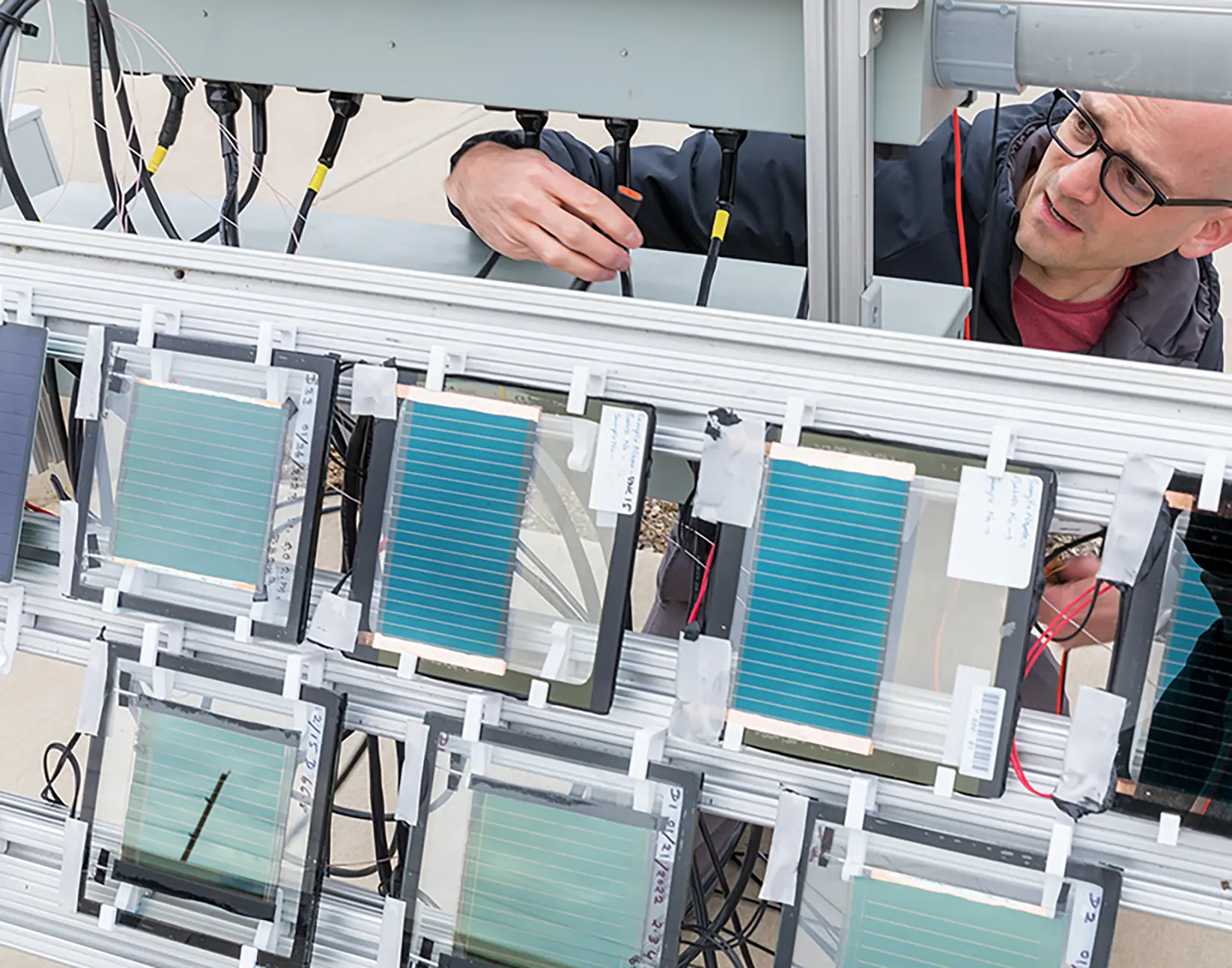 A researcher installs small solar panels at an outdoor test facility.