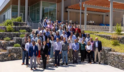 A group of 80 stand outside of a building.