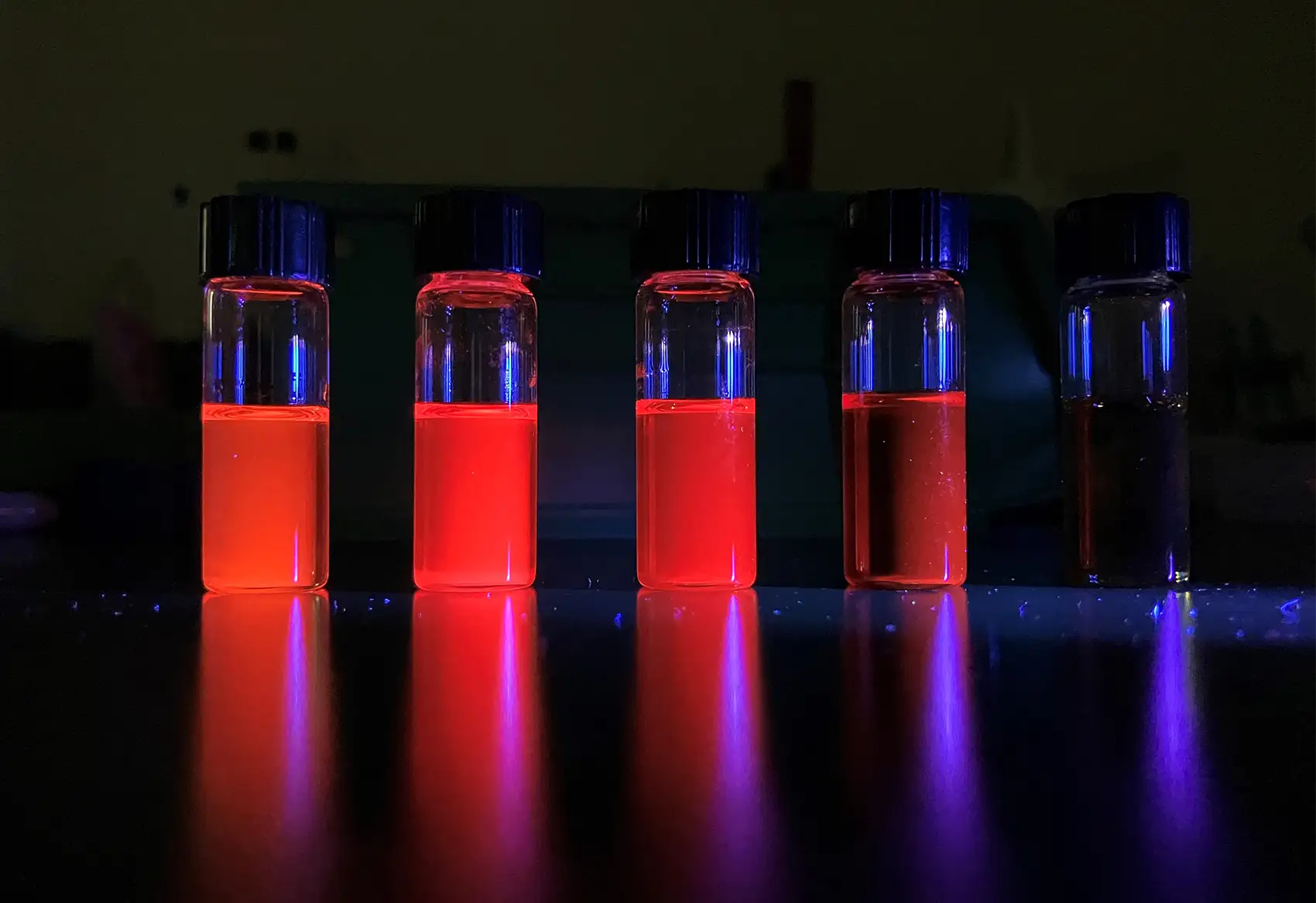 20250822-built-brilliance-zintl-phase-quantum-dots-illuminate-new-opportunities-optoelectronics-qd Image of five vials with glowing liquid inside.