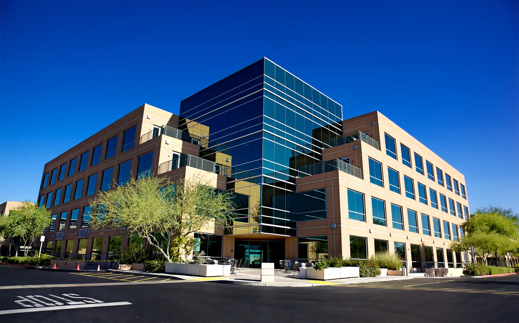20250825-nrel-publishes-strategies-to-reduce-energy-costs-commercial-buildings-including-hospitals-getty-155276196 An office building on a sunny day surrounded by trees.