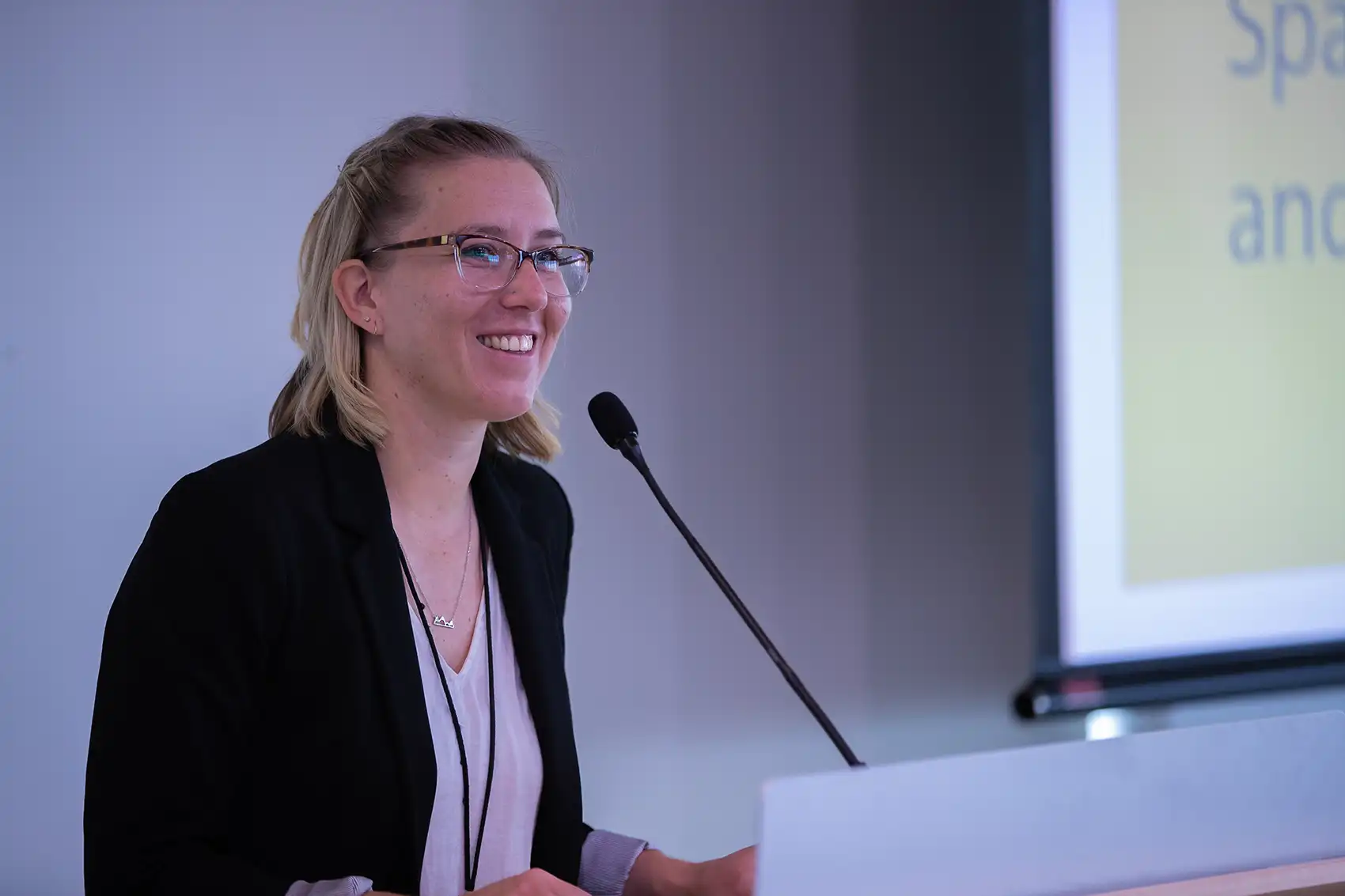 20251210-she-wanted-to-write-fantasy-now-she-is-rewriting-recycling-79160 Taylor smiles while standing behind a podium