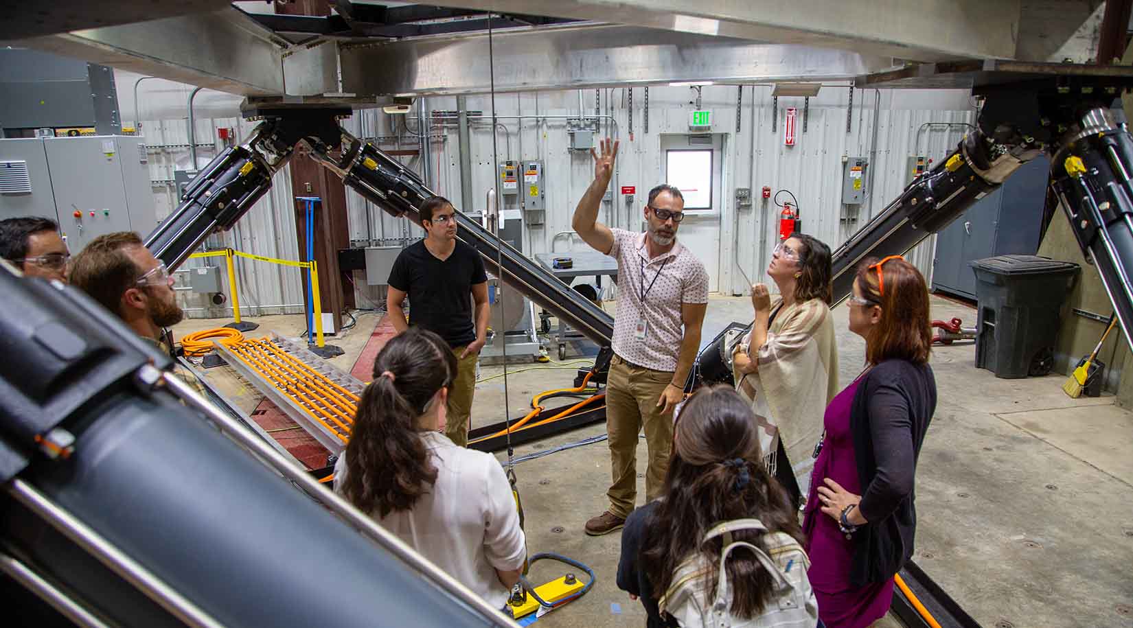 hero-wec-bdy-83443 A photo of a group of people standing underneath large machinery.